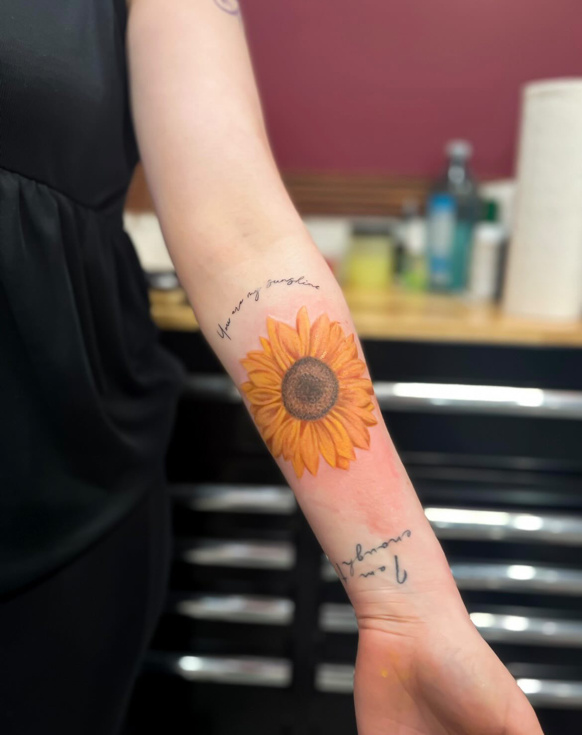 Full color forearm tattoo of a sunflower by tattoo artist Alessandra Clivio.